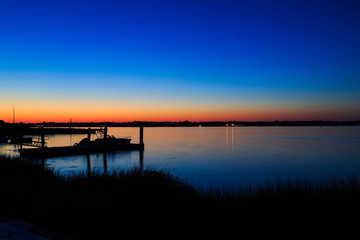 Fototapeta na wymiar Dock, boat and marshes at sunset and blue hour off New Jersey inlet.