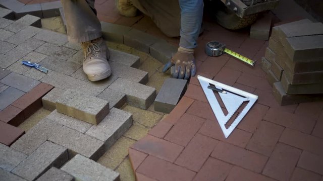 Fitting bricks into a custom designed and cut brick pattern as part of a hardscaping project.