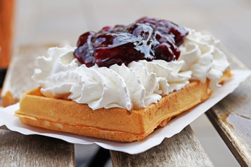 The Belgian wafer. Delicious Belgian waffle with cream, fruit and sauce looks beautiful in the window of the Brussels confectionery store.
