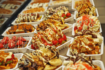 The Belgian wafer. Delicious Belgian waffle with cream, fruit and sauce looks beautiful in the window of the Brussels confectionery store.
