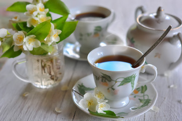 Obraz na płótnie Canvas Tea drinking. Cups with tea and a vase with a jasmine.