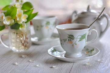 Fototapeta na wymiar Tea drinking. Cups with tea and a vase with a jasmine.