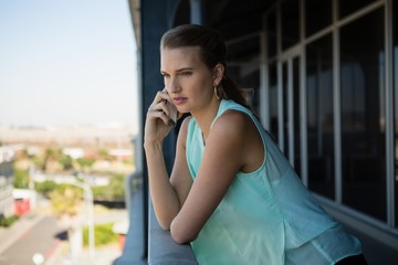 Woman talking on mobile phone in office balcony