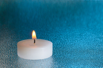 Obraz na płótnie Canvas light candle, on an aquamarine background, vignette