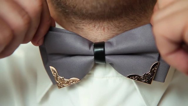 Bow tie under a tuxedo.The young man straightens his tie.