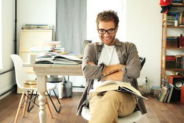 Young man reading book on the background of the desktop