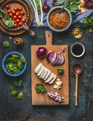 Vegetarian lentil dishes cooking preparation on rustic kitchen table background with cutting board, cooking spoon and utensils, top view. Healthy eating and cooking, clean or diet food concept 