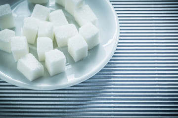 Saucer with sugar cubes on striped background