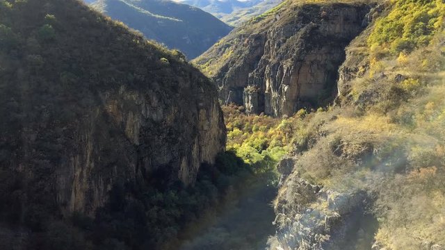 4K aerial shot mountain gorge and cliff with sun leaks