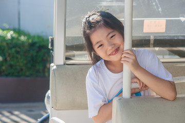 Shoot Asian little cute girl siting in goft car and smiling.