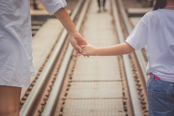 Adorable Family Concept : Woman and children walking on railroad tracks and holding hand together with looking to forward in vintage style.
