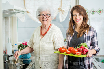 Smiling grandmother with granddaughter cooking in the kitchen.