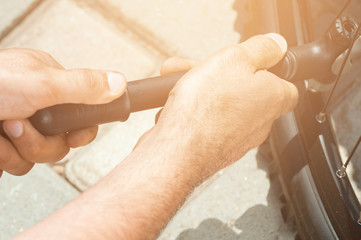 The worker is pumping the bike wheel with instagram orangetoned. Outdoor.