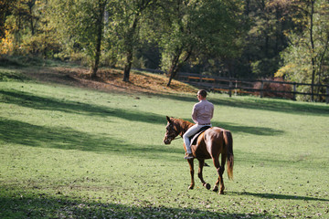 Elegant casually dressed man riding a horse