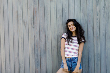 Fototapeta premium Beautiful smiling woman wearing casual clothes, posing outdoors near a wall