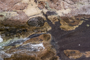 Wasser umspült schwarzes Lavagestein