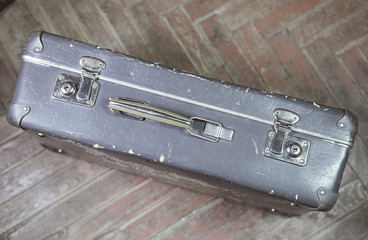 Old shabby suitcase on latches on a wooden floor