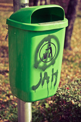 Green garbage can on pillar. Vertical shot