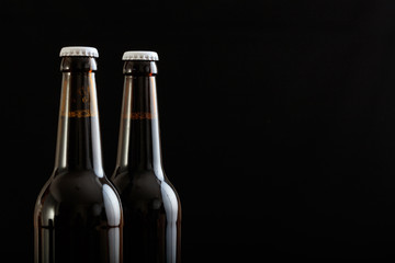 Closeup of two beer bottles isolated on black background