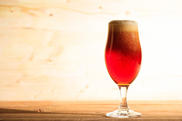 A glass of red beer on a wooden table, copy space