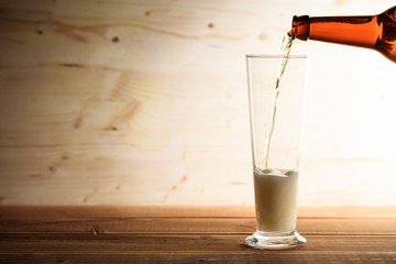 Pouring beer in a glass on a wooden table
