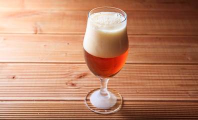 A glass of red beer on a wooden table
