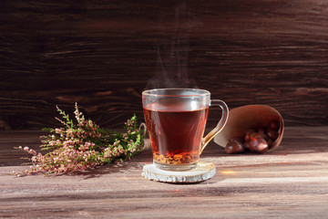 still life with a cup of tea, a bag of chestnuts  and heather on a dark wooden background