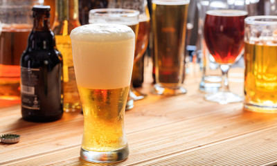 A wooden pub counter, focus on a full frosty glass of beer