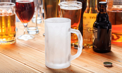 A wooden pub counter, focus on an empty frosty mug of beer