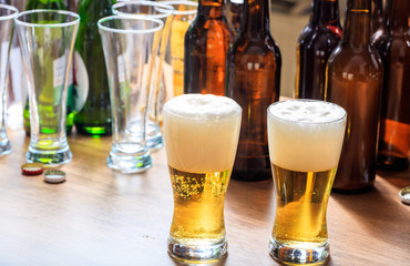 A wooden pub counter, focus on two full glasses of beer