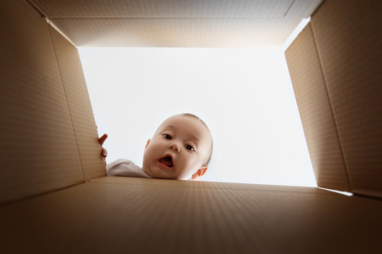 Funny face of baby looking down through cardboard box
