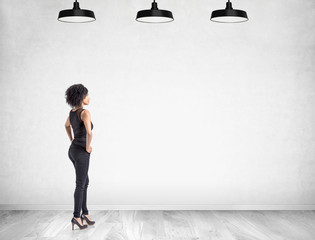 African woman with hands on waist near blank wall