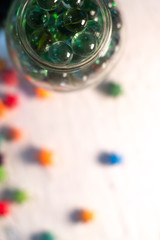 Glass balls in a glass jar with a blurred background.