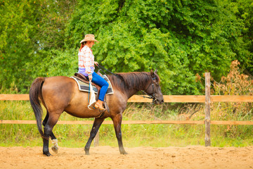 Cowgirl doing horse riding on countryside meadow