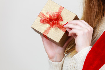 Woman holding golden box gift with red bow in hands