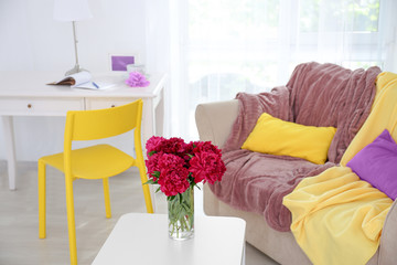 Vase with beautiful peony flowers on table in light modern room