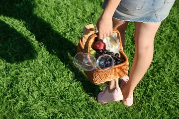 Photo sur Aluminium Pique-nique Woman holding wicker basket with picnic stuff outdoors