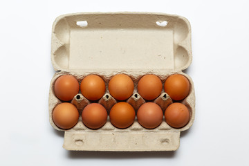 Raw chicken eggs in egg box on white background.