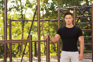 Obraz premium Handsome young man near pull-up bar outdoors