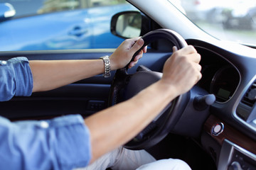 Fototapeta na wymiar Male hands on steering wheel of a car
