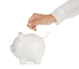 Woman putting coin into cute piggy bank against white background