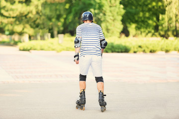 Young man on roller skates in summer park