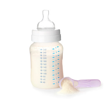 Feeding bottle of baby milk formula and scoop with powder on white background