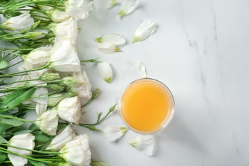 Composition with beautiful flowers and glass of orange juice on light background