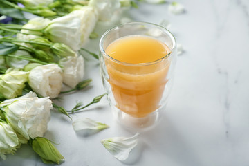 Composition with beautiful flowers and glass of orange juice on light background