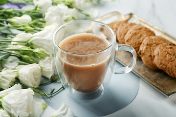 Composition with beautiful flowers, glass cup of coffee and cookies on table