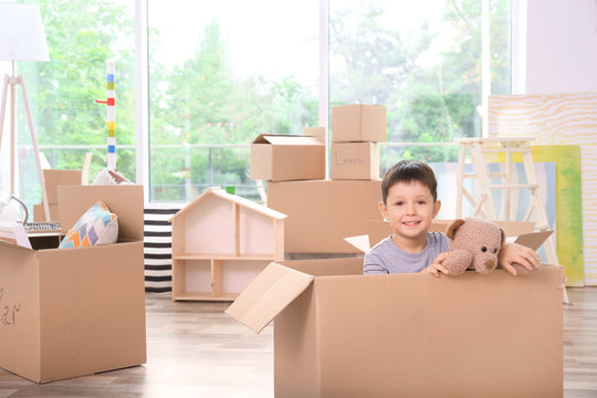 Cute little boy in moving box at new home