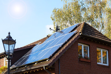 Solarzellen auf dem Eigenheim mit Sonne am blauen Himmel