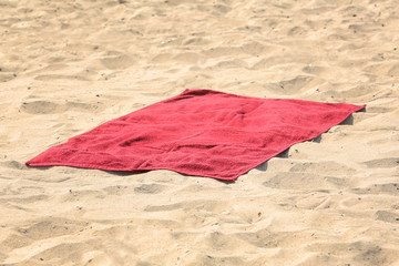 Red beach towel on sand