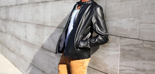 Fashion man wearing a black leather jacket in the city on a gray background